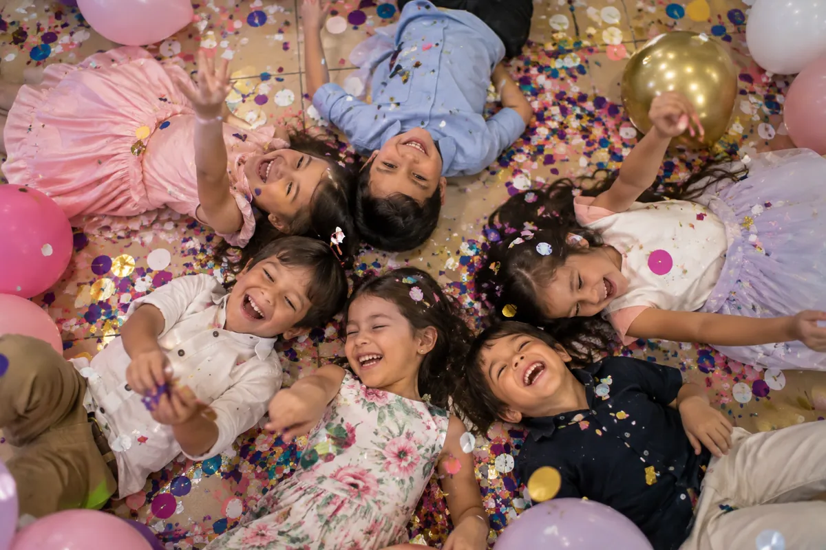Niños riendo con confeti y globos