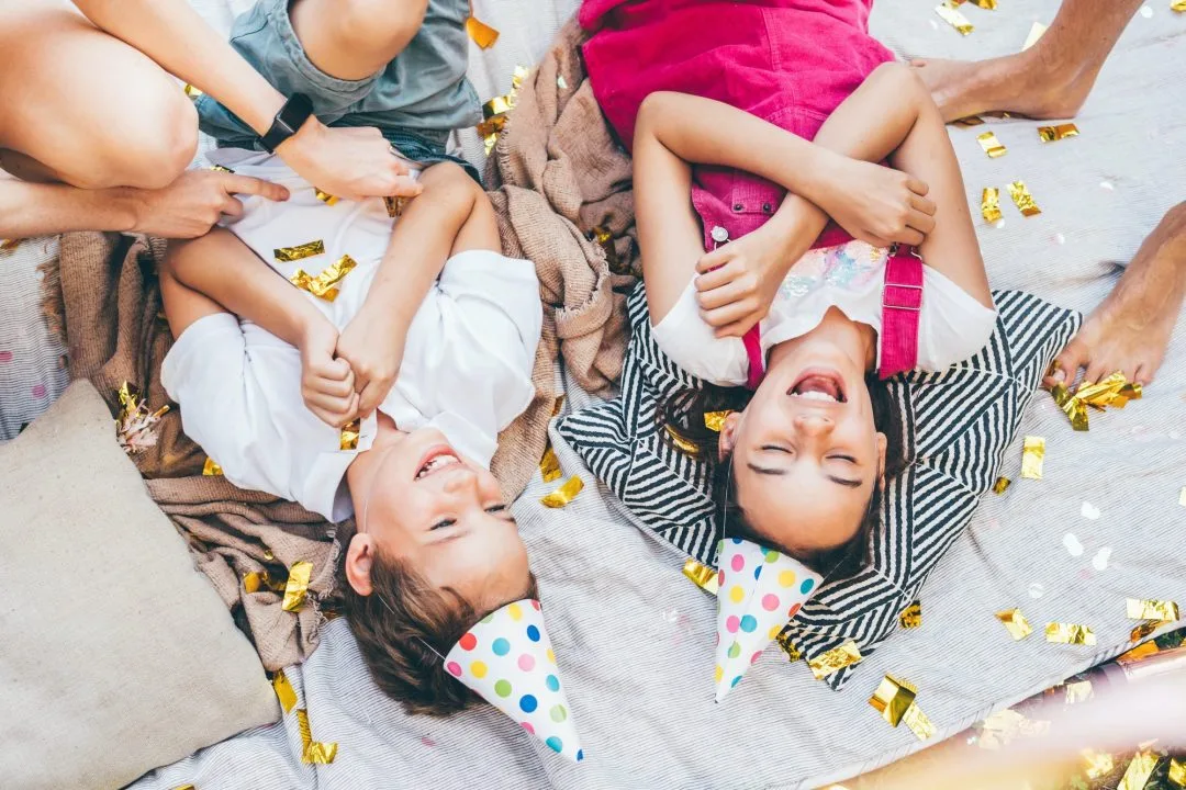 Niños riendo con confeti y globos